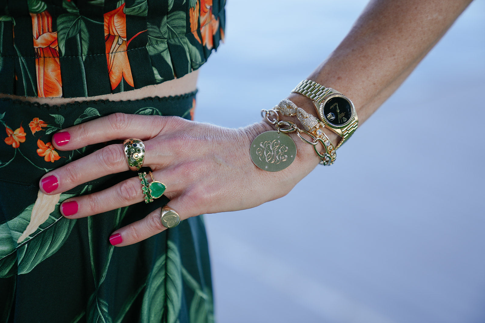 An engraved gold disc bracelet and stacked rings on the wrist
