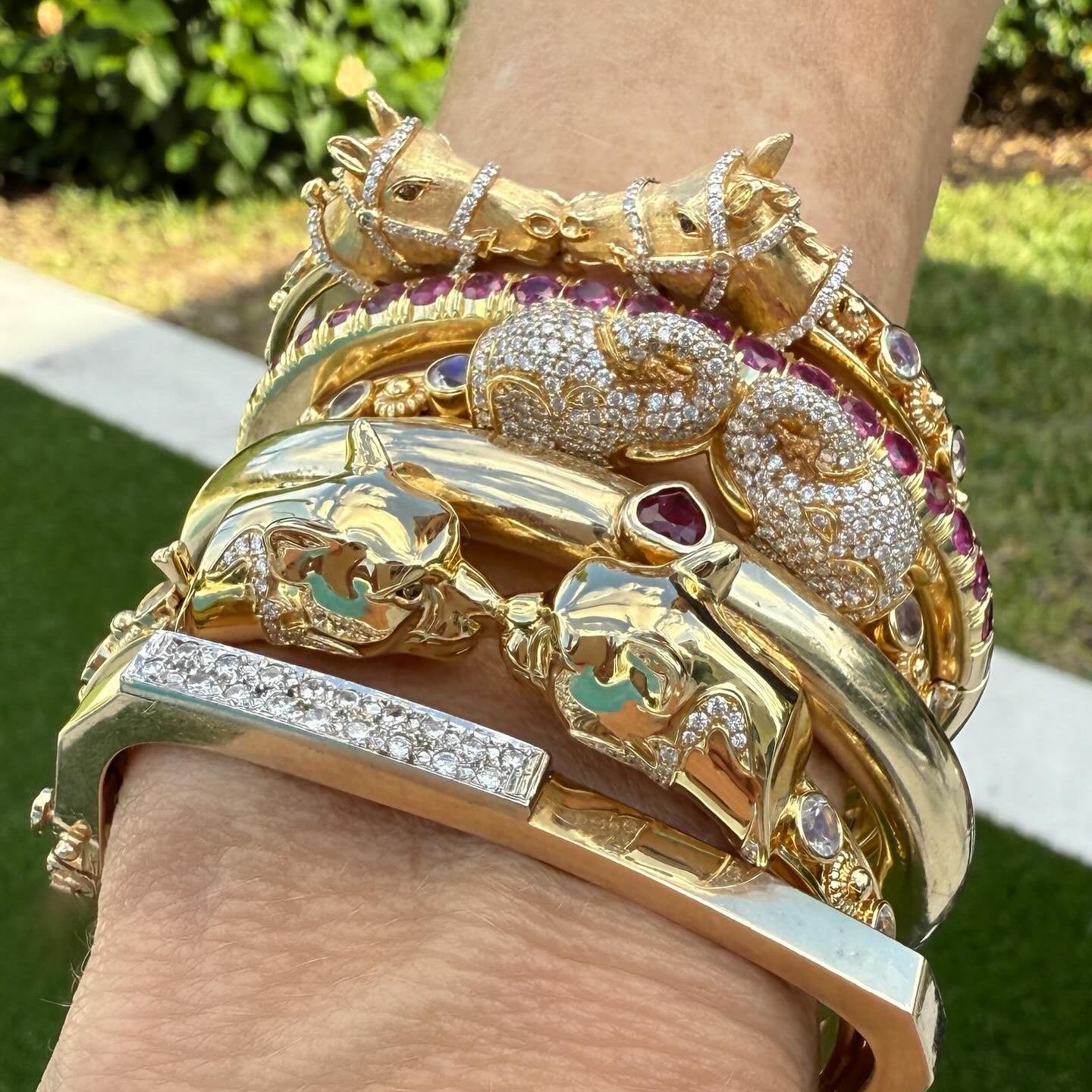 Gold animal bangles with rubies and diamonds, stacked on a wrist