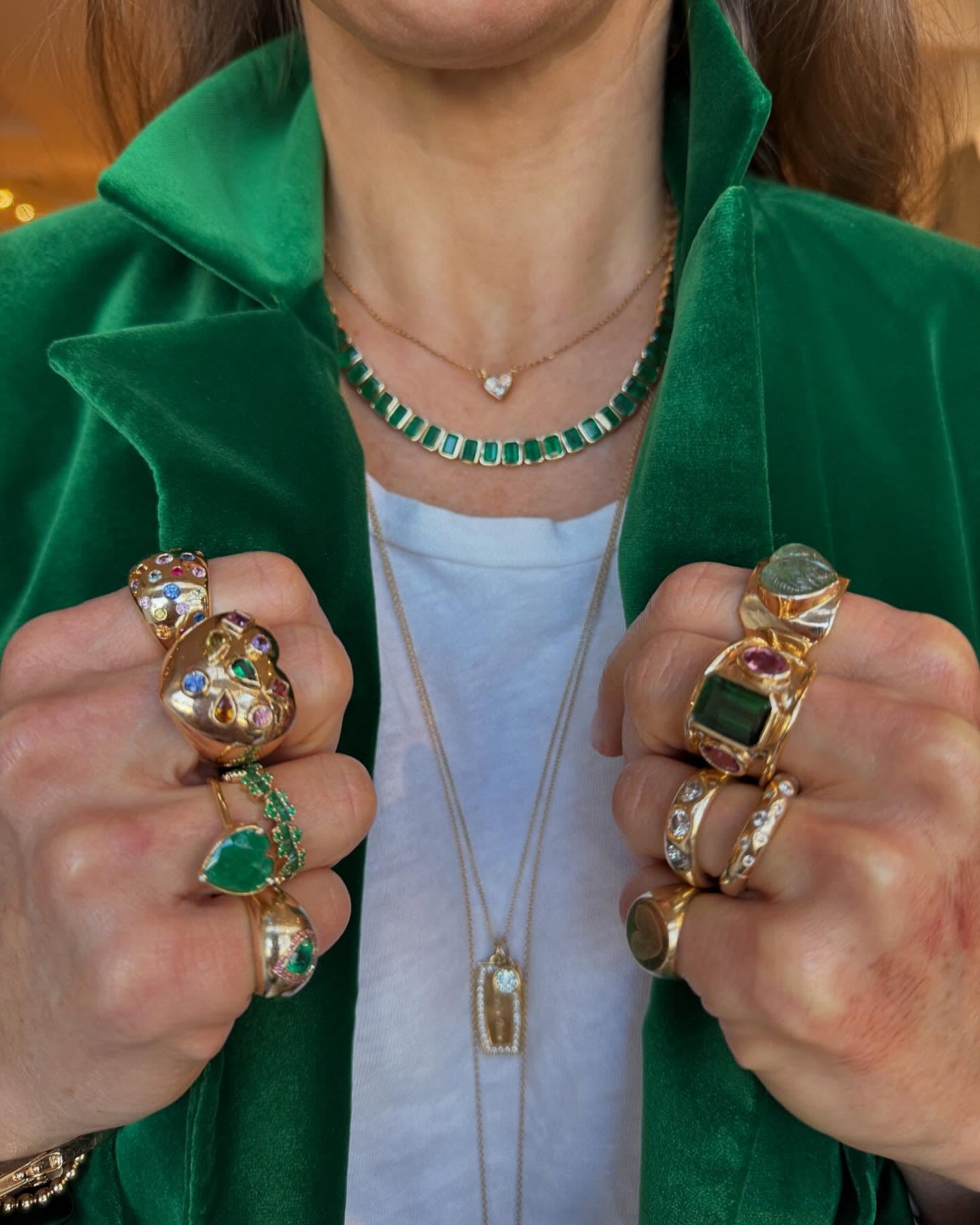 Gold and gemstone rings and an emerald necklace with a green velvet jacket