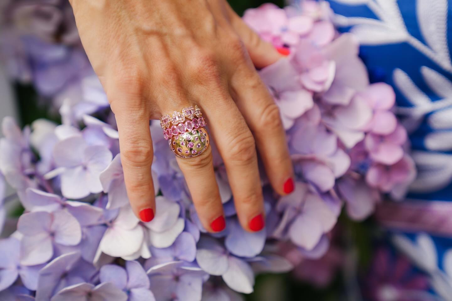 Pink sapphire rings on a hand over hydrangeas