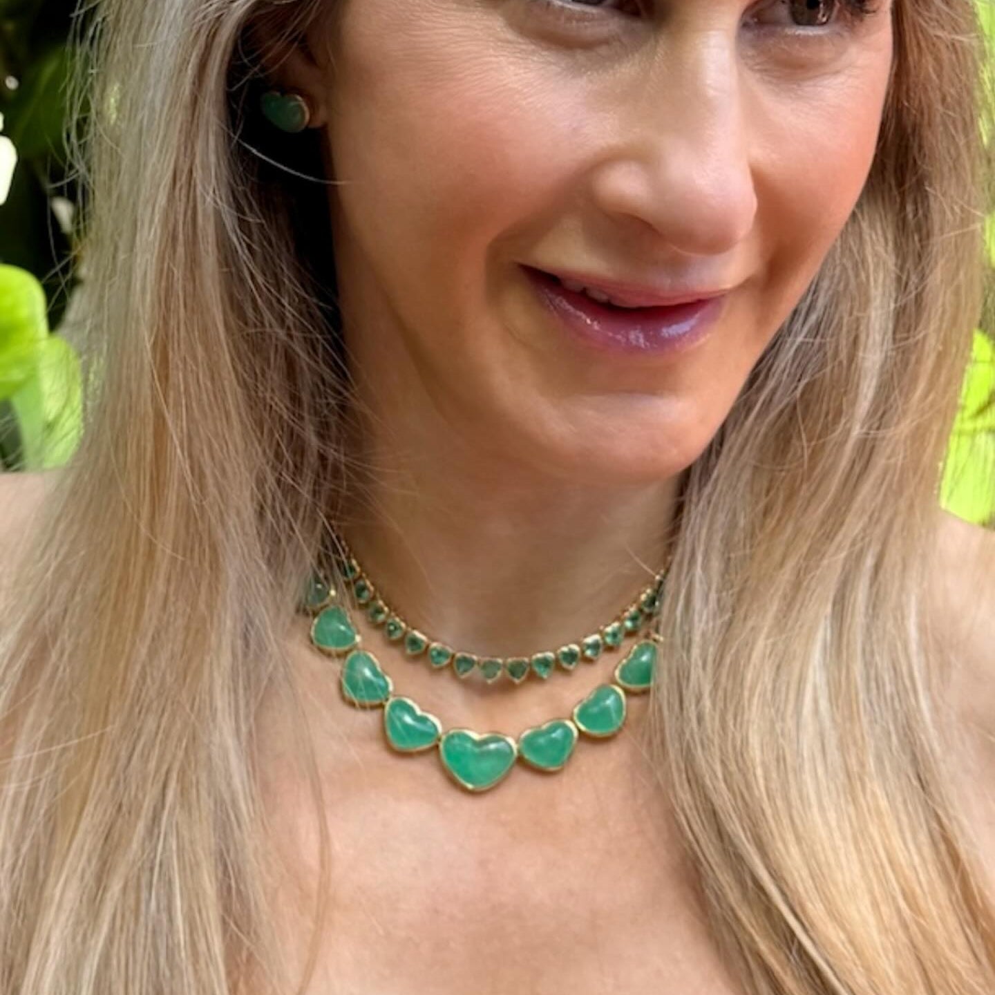 An emerald heart necklace worn with a white tee
