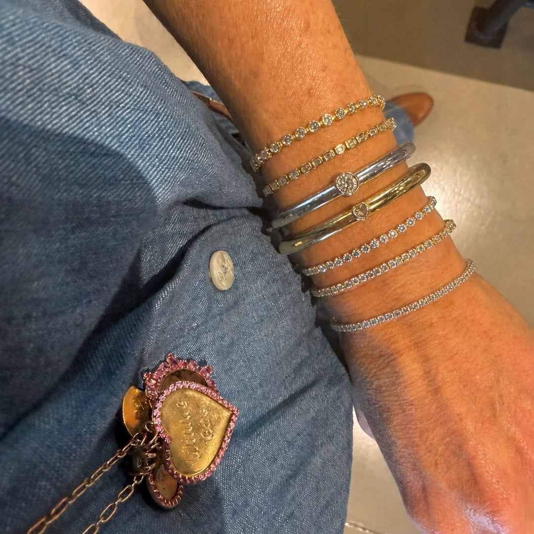 Diamond bangles and a charm on a denim shirt