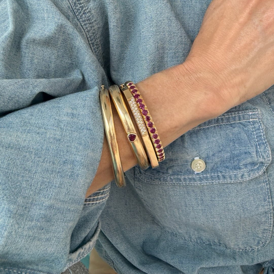 Gold cuffs with rubies on a denim shirt